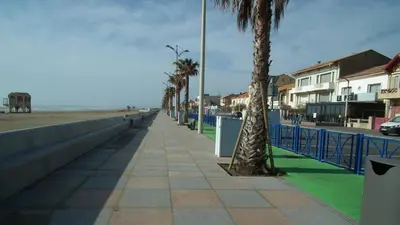 a sidewalk next to a beach with palm trees at Maison près des plages in Port-la-Nouvelle