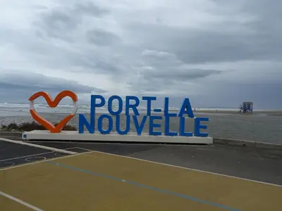 a sign for a tennis court next to the ocean at Maison près des plages in Port-la-Nouvelle