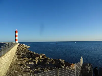 a red and white lighthouse next to the ocean at Maison près des plages in Port-la-Nouvelle