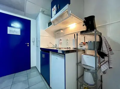 a small kitchen with a sink and a blue door at Zen studio ※ parking - piscine in Carcassonne