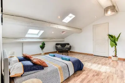 a bedroom with a large bed and a chair at El Marty - central - climatisation - parking gratuit - wifi in Carcassonne