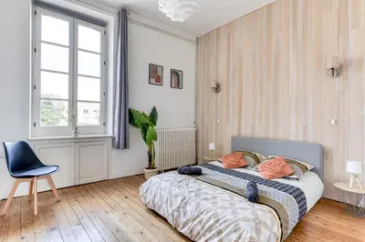 a bedroom with a bed and a chair and a window at El Marty - central - climatisation - parking gratuit - wifi in Carcassonne