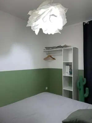 a bedroom with a white bed and a chandelier at Appartement central à Castelnaudary in Castelnaudary