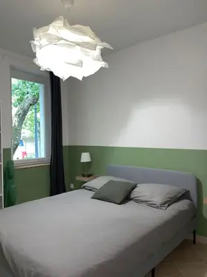 a bedroom with a bed with a chandelier and a window at Appartement central à Castelnaudary in Castelnaudary