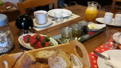 a wooden table topped with a table with bread and strawberries at B&B La Ferme de Loubens in Loubens-Lauragais