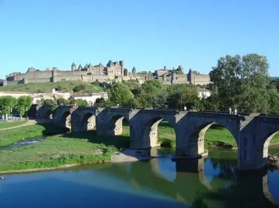 a bridge over a river with a castle in the background at Le studio de Simon au pied de la cité in Carcassonne