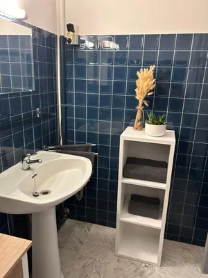a bathroom with a white sink and a blue tiled wall at Le studio de Simon au pied de la cité in Carcassonne