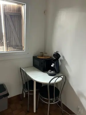 a small table with two chairs and a microwave at Le studio de Simon au pied de la cité in Carcassonne