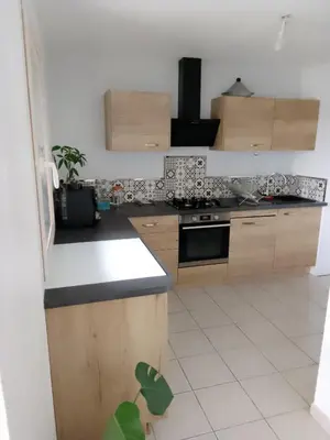 a kitchen with wooden cabinets and a white tile floor at Agréable pavillon in Nailloux