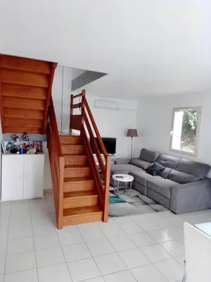 a living room with a staircase and a couch at Agréable pavillon in Nailloux