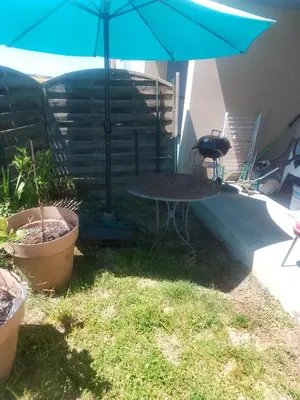 a table with a blue umbrella in a yard at Agréable pavillon in Nailloux