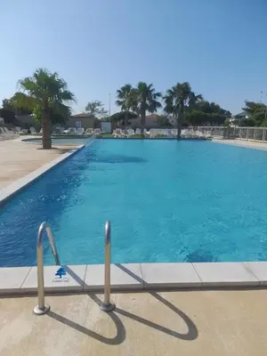 a large swimming pool with blue water at MOBILHOME OLIVIER - Camping avec piscine à Port-la-Nouvelle in Port-la-Nouvelle