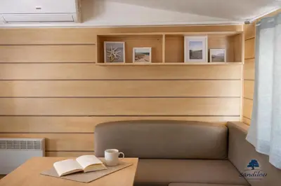 a room with a bench and a table with a book at MOBILHOME OLIVIER - Camping avec piscine à Port-la-Nouvelle in Port-la-Nouvelle