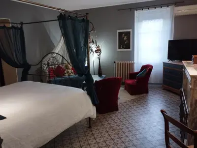 a bedroom with a bed and two chairs and a television at L Aparté en Corbières in Ferrals-lès-Corbières