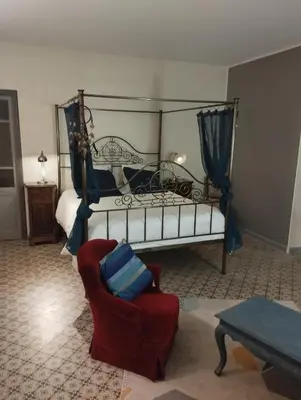 a bedroom with a bed and a red chair at L Aparté en Corbières in Ferrals-lès-Corbières