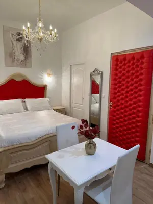 a bedroom with a bed and a table and a red door at Petit studio presbytère dans L'Église in Narbonne