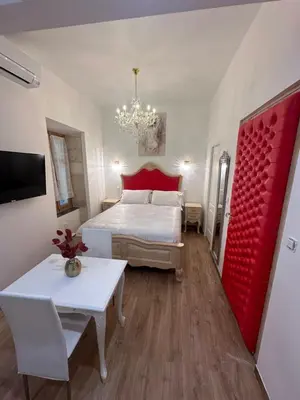 a bedroom with a bed and a table and a red door at Petit studio presbytère dans L'Église in Narbonne