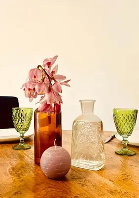 a table with three glass vases and a candle on it at Le Victor Hugo de la Robine in Narbonne