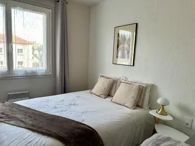 a bedroom with a bed with white sheets and a window at Le Victor Hugo de la Robine in Narbonne
