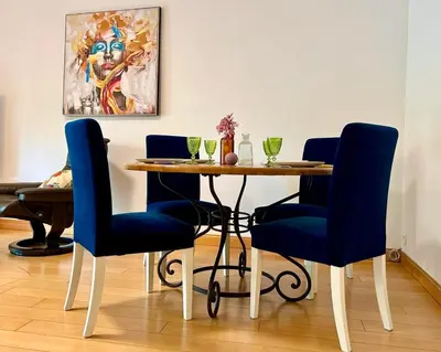 a dining room table with blue chairs and a painting at Le Victor Hugo de la Robine in Narbonne