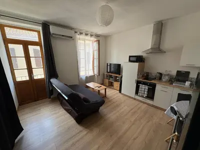 a living room with a couch and a kitchen at Appartement T2 avec balcon proche centre-ville NARBONNE in Narbonne
