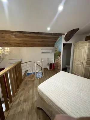 a bedroom with a white bed and wooden floors at Suite a Mezzanine dans l'Église du Couvent in Narbonne