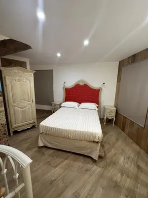 a bedroom with a large bed with a red headboard at Suite a Mezzanine dans l'Église du Couvent in Narbonne