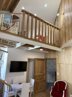 a living room with a staircase and a table and chairs at Suite a Mezzanine dans l'Église du Couvent in Narbonne