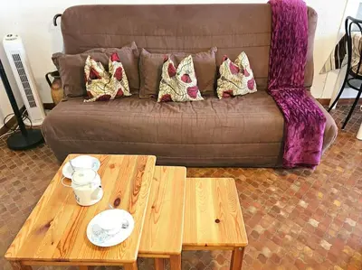 a living room with a couch and two tables at Logis des Palmiers YourHostHelper in Gruissan