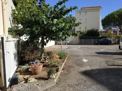 a parking lot with a tree and a building at Studio L'air marin in Gruissan