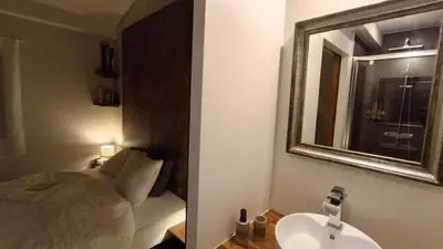 a bathroom with a sink and a mirror and a bed at Le Chant des Pierres in Saint-Pierre-des-Champs