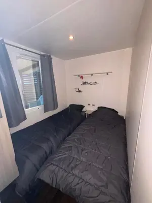 a kitchen with a refrigerator and a microwave and a window at MOBILE HOME Clim-Piscine -Terrasse -Parking -6 personnes in Port-la-Nouvelle