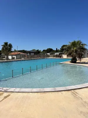 a large swimming pool with blue water and palm trees at MOBILE HOME Clim-Piscine -Terrasse -Parking -6 personnes in Port-la-Nouvelle