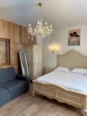 a bedroom with a bed and a chair and a chandelier at Studio dans L'Eglise du Couvent in Narbonne