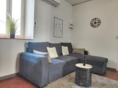 a blue couch in a living room with a clock at Le Barès in Carcassonne