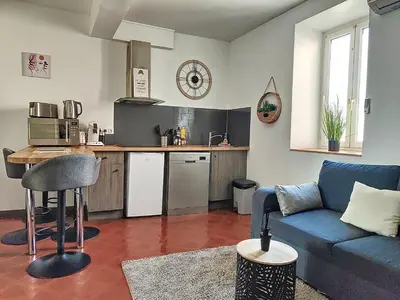 a living room with a blue couch and a kitchen at Le Barès in Carcassonne