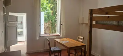 a table and chairs in a room with a window at Clim et extérieur entre mer, garrigue et réserve africaine in Portel-des-Corbières