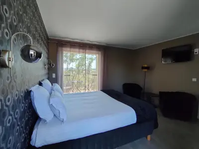 a hotel room with a bed and a window at Hôtel Restaurant L'Art des Mets by Côté Jardin in Conilhac-Corbières