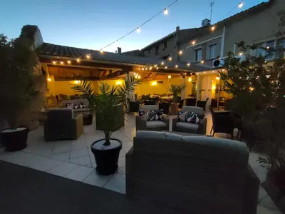 a patio with couches and tables and lights at Hôtel Restaurant L'Art des Mets by Côté Jardin in Conilhac-Corbières