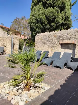 a row of blue benches sitting next to a stone wall at Hôtel Restaurant L'Art des Mets by Côté Jardin in Conilhac-Corbières