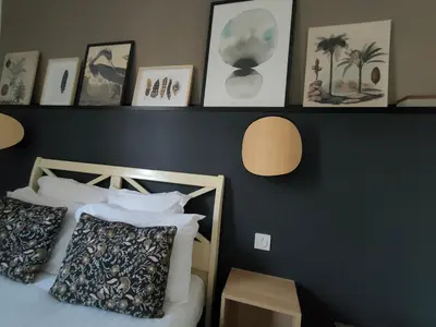 a bedroom with a bed and some pictures on the wall at Hôtel Restaurant L'Art des Mets by Côté Jardin in Conilhac-Corbières