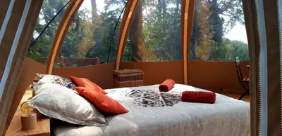 a bed in a room with a large window at Le Mobil'Dôme à Marie in Cambounès