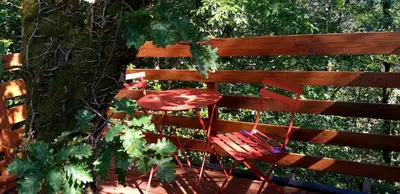 a red chair sitting next to a wooden fence at Le Mobil'Dôme à Marie in Cambounès