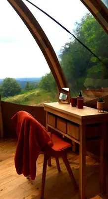 a table with a laptop on it in front of a window at Le Mobil'Dôme à Marie in Cambounès