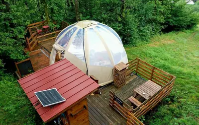 an umbrella and a table with a laptop on a deck at Le Mobil'Dôme à Marie in Cambounès