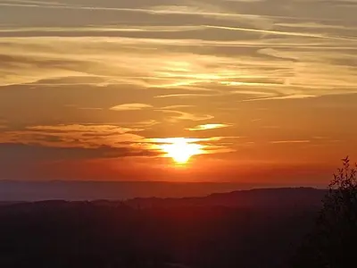 a sunset with the sun setting over the mountains at Le Mobil'Dôme à Marie in Cambounès