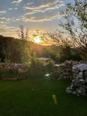 a sunset in a yard with a stone wall at Gîte col de la lauze avec vue sur le château de Montségur in Montferrier