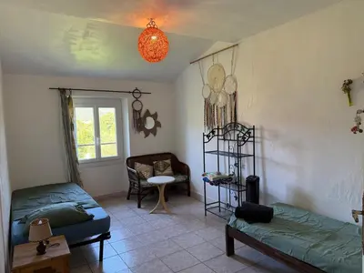 a living room with two beds and a chair at hOMe-Shanti Galamus -- Relais Rando - vélo - moto in Saint-Paul-de-Fenouillet