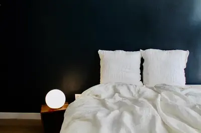 a bed with white sheets and a blue wall at Maison Merci - Maison d'hôtes in Carcassonne