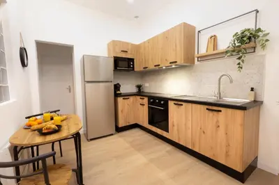 a kitchen with wooden cabinets and a table and a refrigerator at Balda'Quand Médiéval in Carcassonne